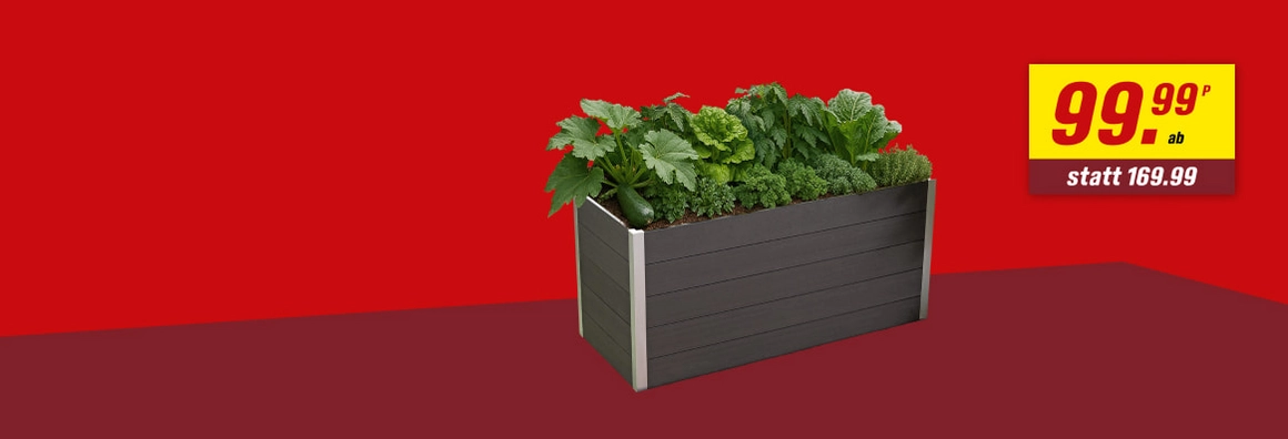 Ein dunkelgraues Hochbeet, bepflanzt mit Gemüse vor einem roten Hintergrund.